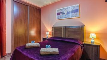 A hotel room with a large bed, two bedside tables with lamps, a wooden wardrobe, and a world map on the wall.