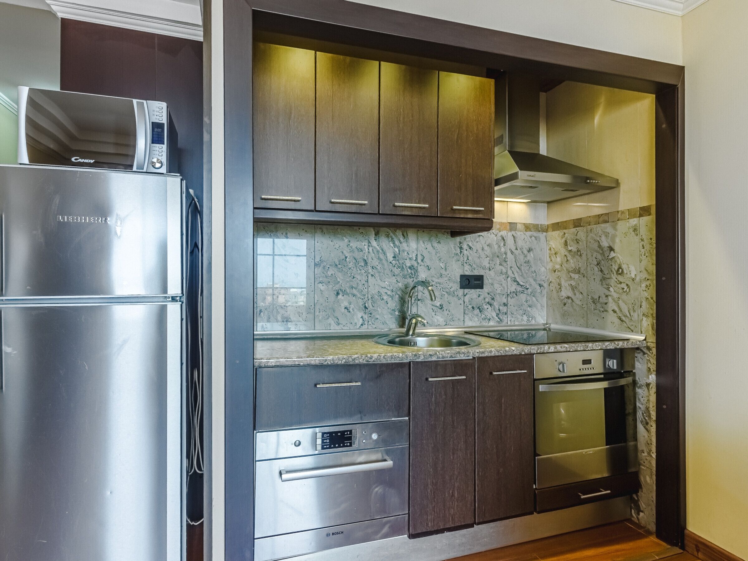 Una cocina moderna con electrodomésticos de acero inoxidable, armarios de madera oscura y salpicadero de mármol.