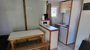 A compact kitchen with a wooden table and bench, a microwave, a coffee maker, and a sink.