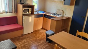 Une cuisine compacte équipée d’un four à micro-ondes, d’une cuisinière, d’un évier et d’une petite table à manger.