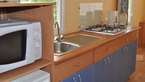 Une cuisine compacte équipée d’un four à micro-ondes, d’un évier, d’une cuisinière et de placards.