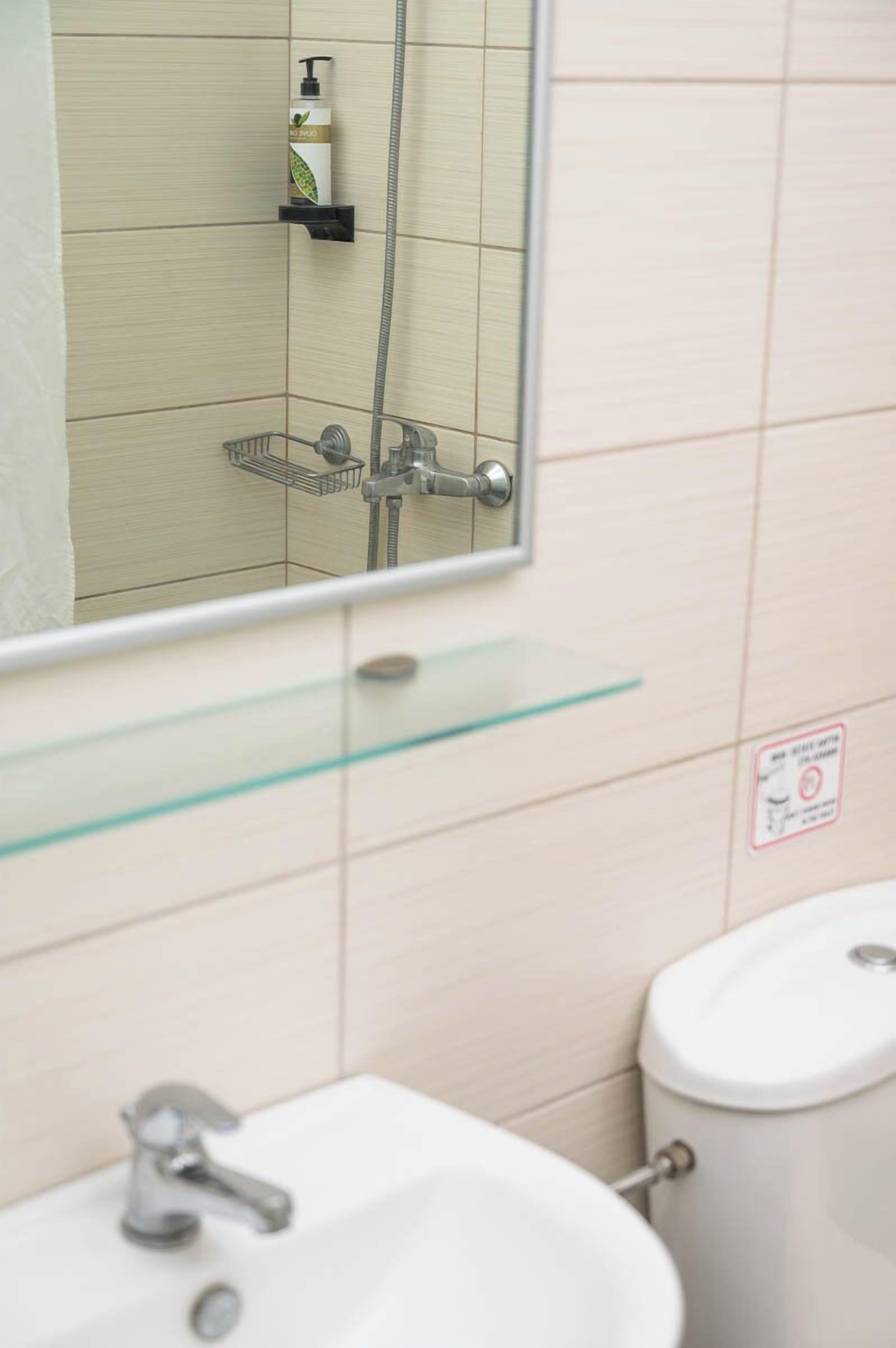 A bathroom with a white sink, a mirror, and a shower.