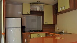 Eine kompakte Küche mit Kühlschrank, Herd, Spüle und einem kleinen Esstisch mit Stühlen.