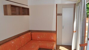 Ein Ecksofa mit floralem Bezug, ein Holztisch und eine Tür mit Vorhängen.
