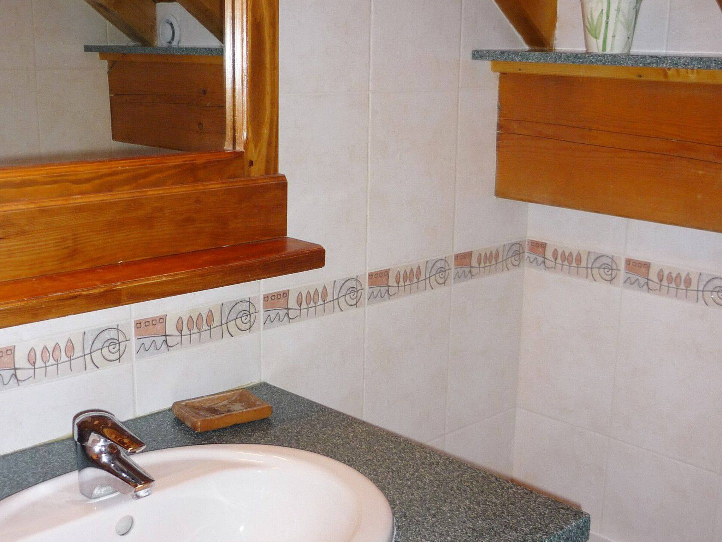 Une salle de bain avec un lavabo blanc, un meuble-lavabo en bois et un miroir.