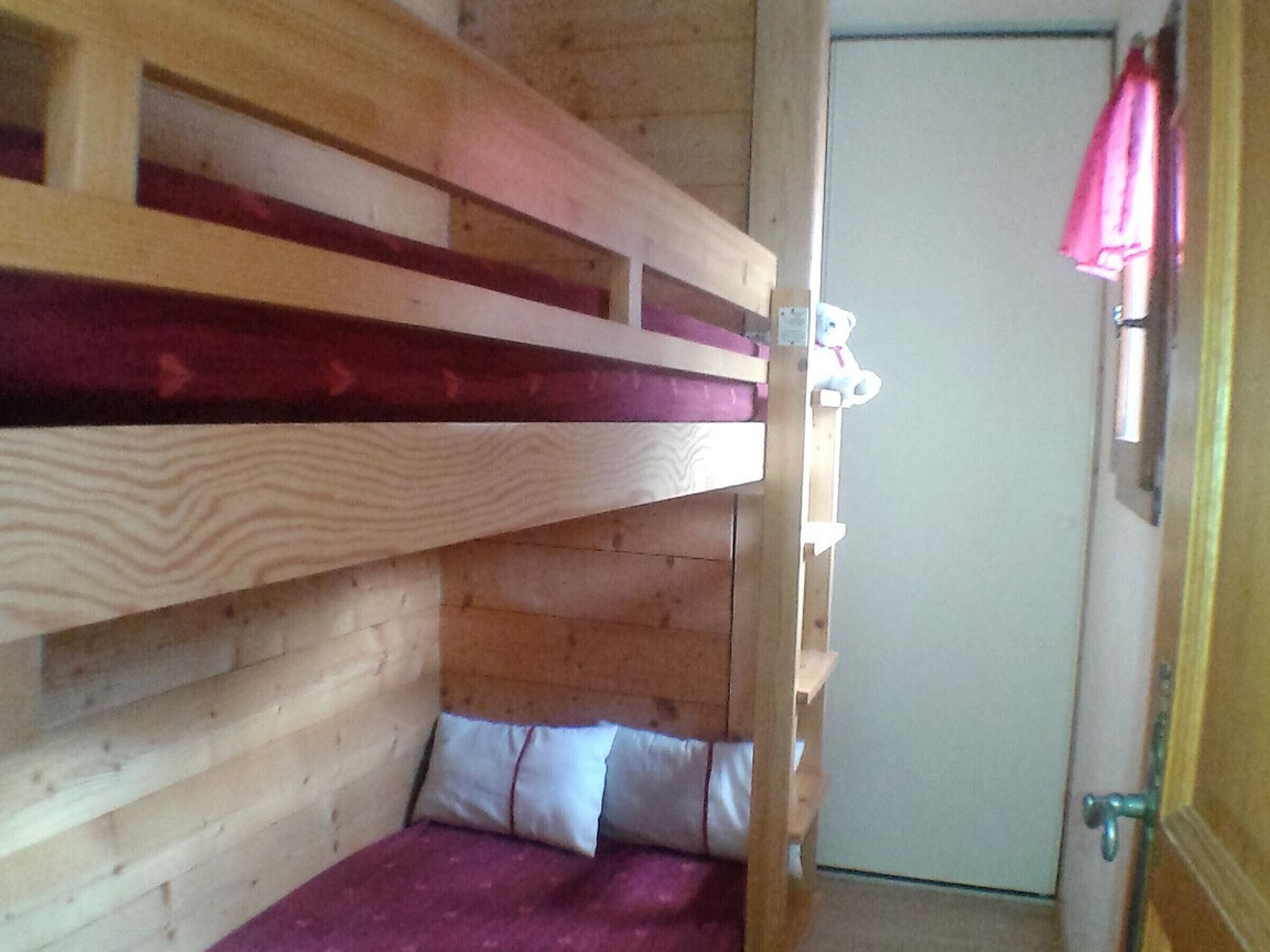 A bunk bed room with wooden walls and a door.