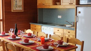 Interior em madeira com uma mesa de jantar posta para quatro pessoas, micro-ondas e lava-louças.