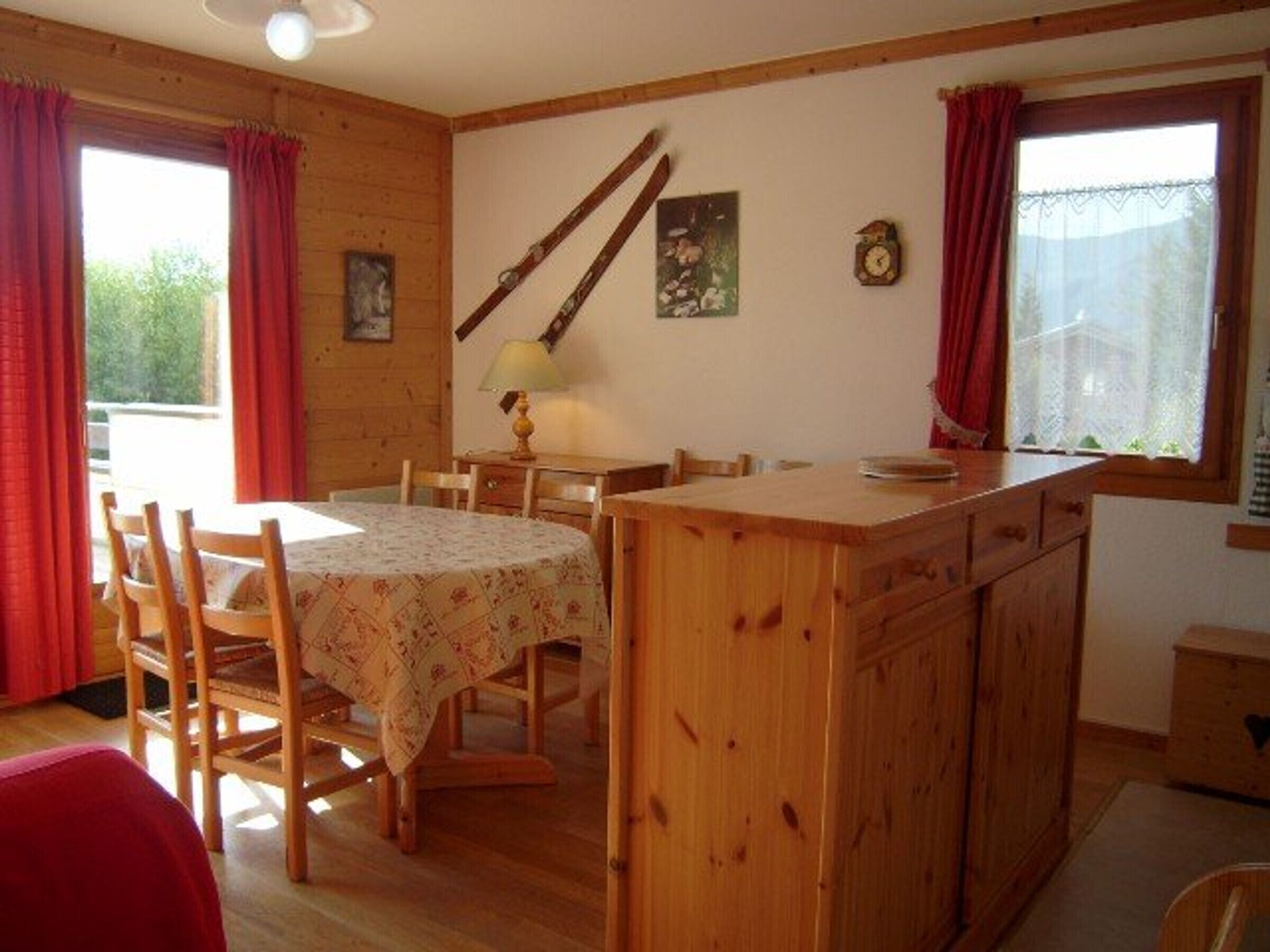 Un intérieur en bois comprenant une table à manger, des chaises, un buffet en bois, une lampe et une horloge murale.