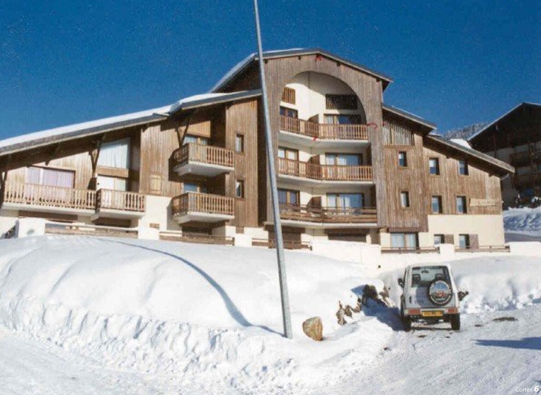 A wooden chalet with multiple balconies and a ski lift nearby.