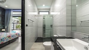 A modern bathroom with a glass shower, a white bathtub, and a toilet. - 3BR Near Beach Tub & Pool Table V204 (Rawai)