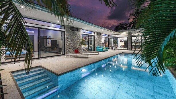 A modern house with a swimming pool, stone walls, and glass doors. - 3BR Near Beach Tub & Pool Table V204 (Rawai)