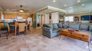 A spacious living area with a large gray sofa, a wooden coffee table, and a dining table with chairs. - Bayside Gem - Beachfront - Vibrant - Ocean Breeze (San Diego)