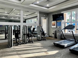 Une salle de sport équipée de machines de cardio, d’appareils de musculation et d’un tapis de course.