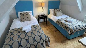 A room with two beds, a nightstand, a lamp, and a ceiling light. - 2 Bed Apartment - Sleeps 4 - Parking - Wifi (Doncaster)