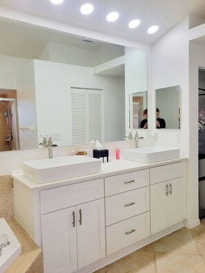 Une salle de bain moderne avec un grand miroir, deux lavabos et une douche à l’italienne.