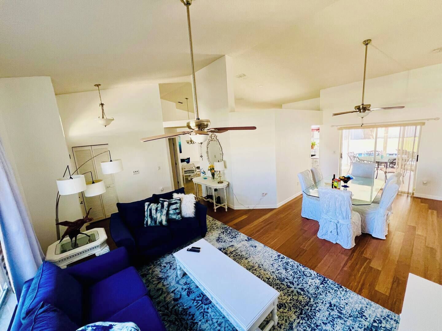 A spacious living room with a blue sofa, a white coffee table, and a ceiling fan.