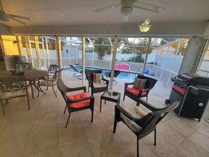 Une terrasse extérieure aménagée avec des meubles en osier, un barbecue et une vue sur la piscine du jardin.