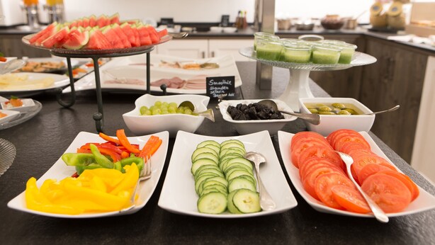 Un buffet proposant une variété d’aliments, notamment des tranches de pastèque, de concombre et de tomate.