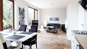 Un salon moderne comprenant un coin repas, une cuisine et un téléviseur.
