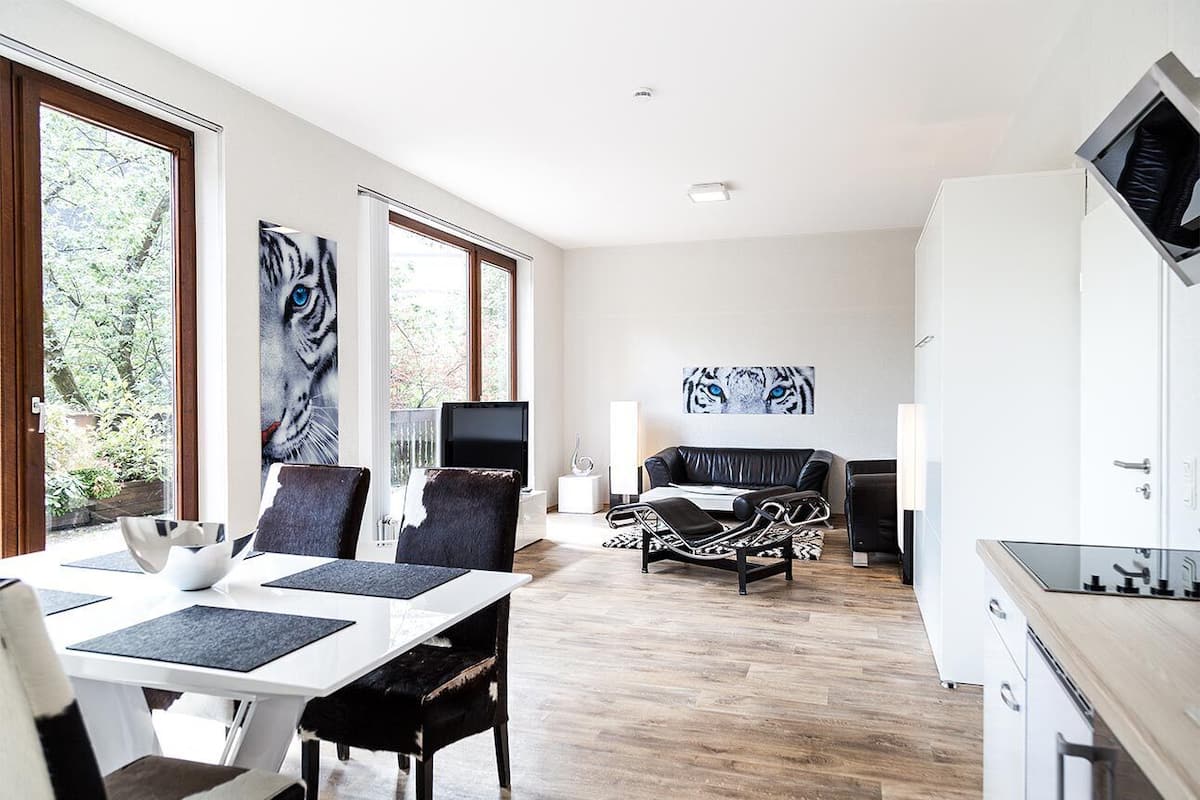 A modern living room with a dining area, a kitchen, and a TV.