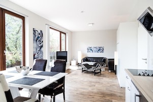 Ein modernes Wohnzimmer mit Essbereich, Küche und Fernseher.