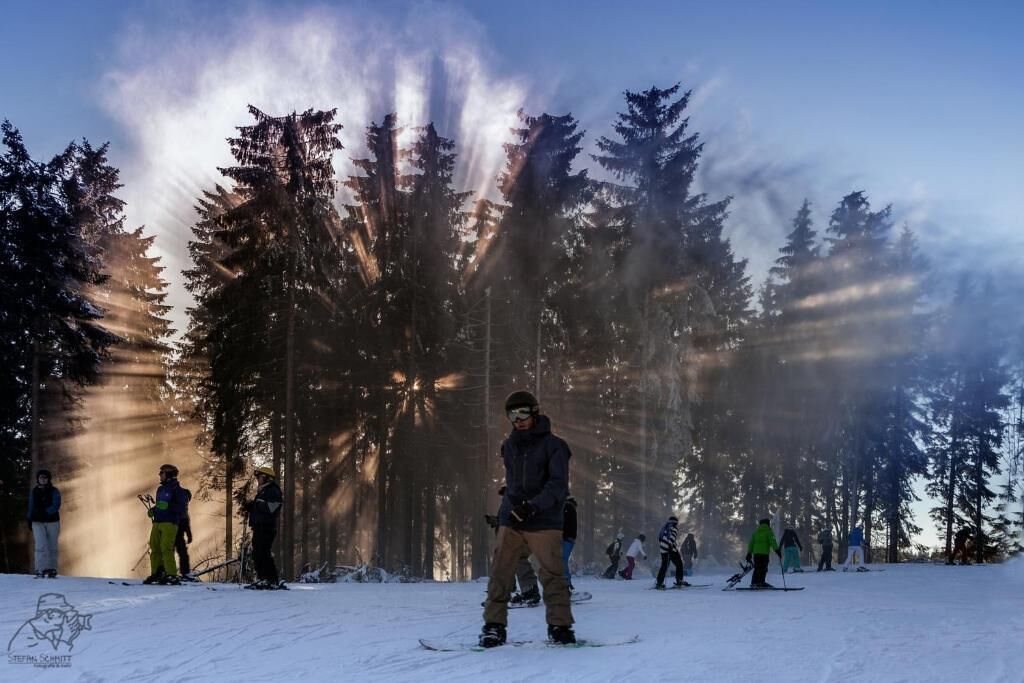Ein verschneiter Skipisten mit Skifahrern und Snowboardern.