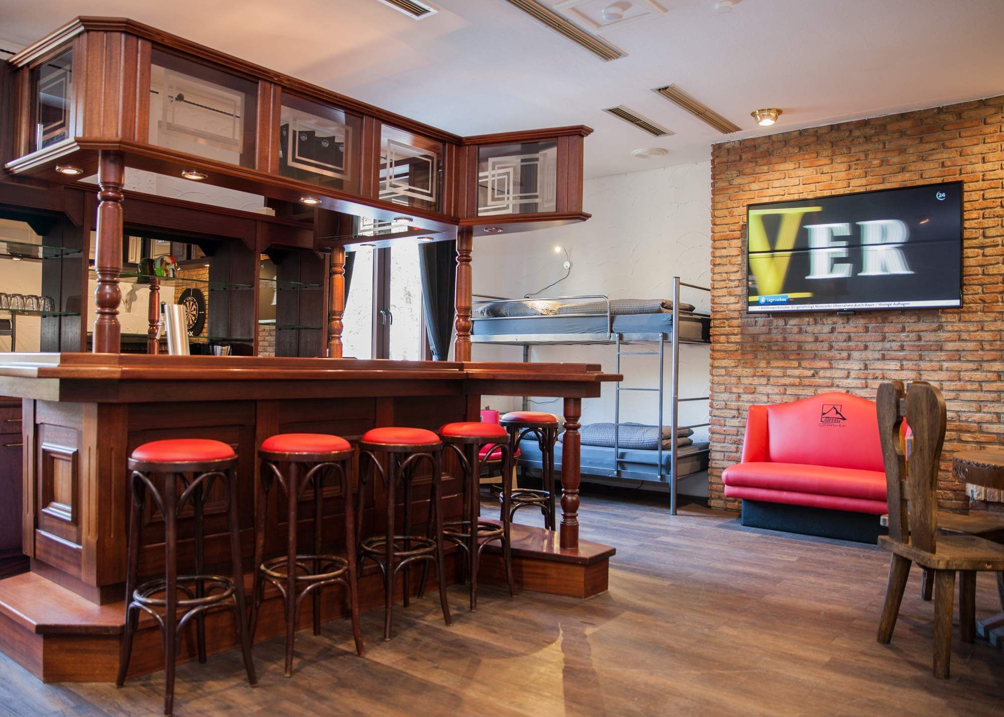 A bar area with stools, a red couch, and a brick wall with a 'VER' sign.