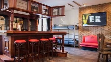 A bar area with stools, a red couch, and a brick wall with a 'VER' sign.