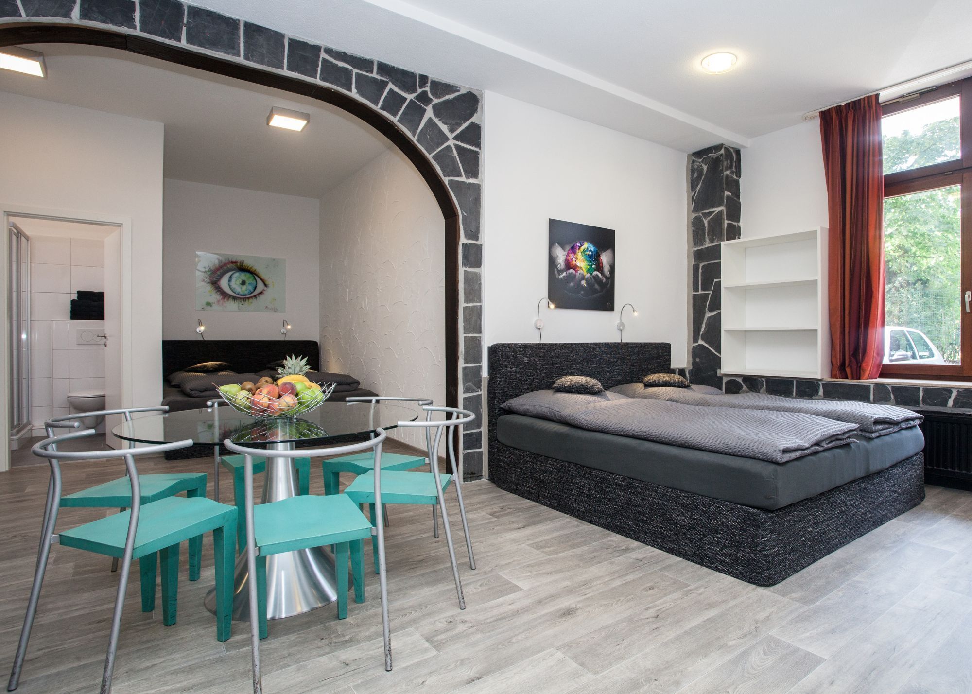 Une chambre moderne comprenant un lit, une table à manger avec des chaises, un coin cuisine et une salle de bain.