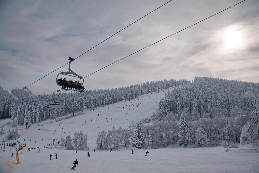 A ski lift with passengers ascending a snowy slope.