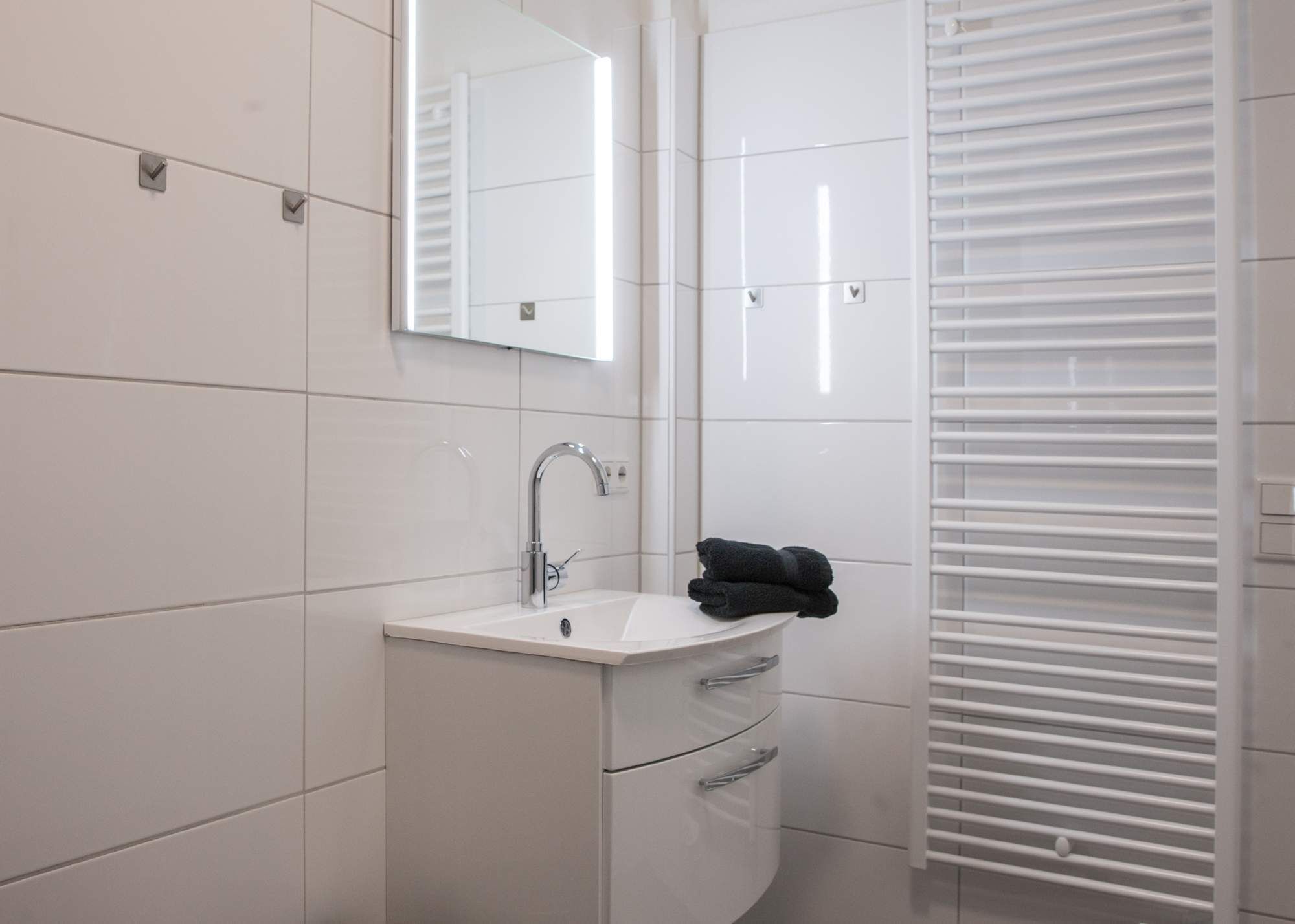 A modern bathroom with a white sink, a mirror, and a towel on the counter.