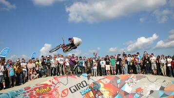 Een skateboarder voert een truc uit in een skatepark, terwijl een menigte toeschouwt.