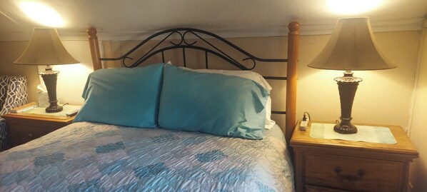 A bed with a headboard, two bedside tables with lamps, and a patterned bedspread.
