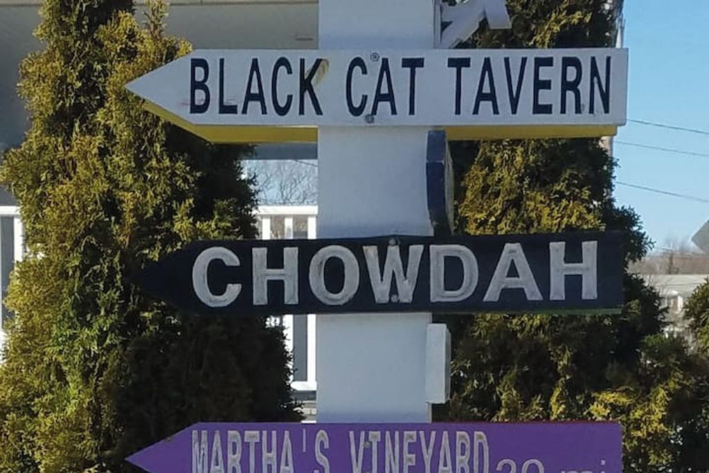 En vägskylt med texten ”BLACK CAT TAVERN” och ”CHOWDAH”.