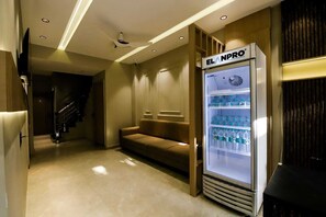 A hotel corridor with a seating area, a minibar, and a staircase. - Hotel Maheshwari Inn (Ujjain)