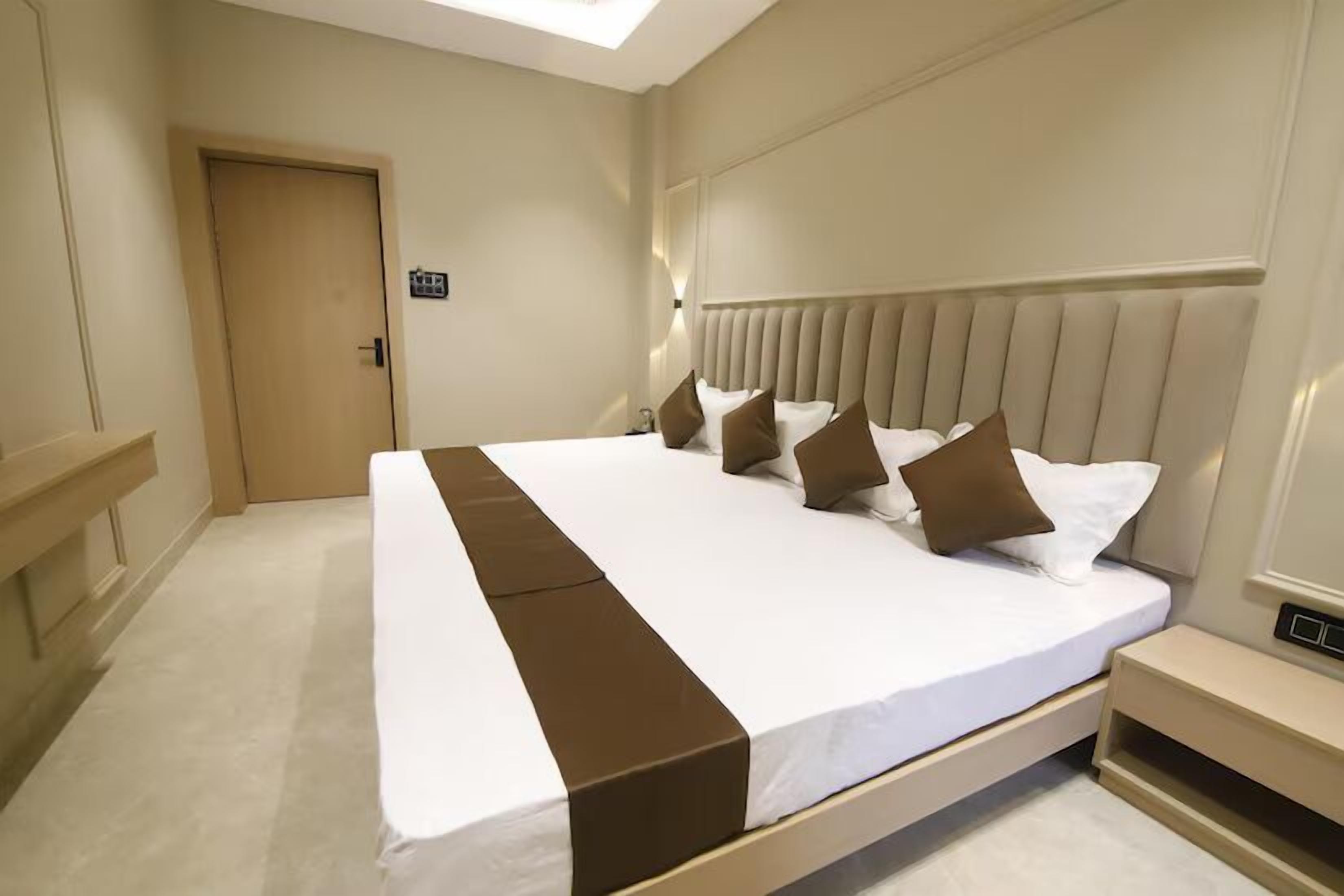 Een netjes ingerichte hotelkamer met een groot bed, een nachtkastje en een deur.