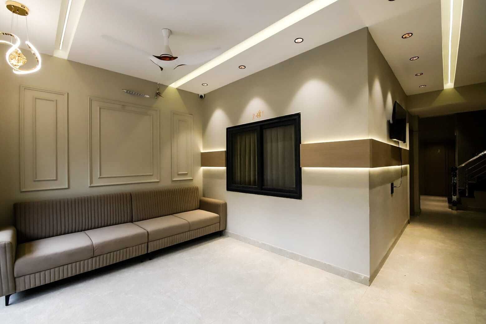 Un interior moderno con sofá, iluminación empotrada y televisor montado en la pared.