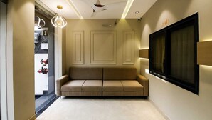 Un interior moderno con un sofá color crema, iluminación empotrada en el techo y un ventanal con cortinas.