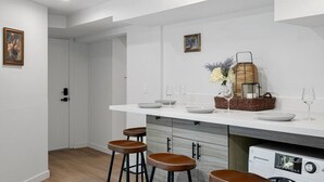 A modern kitchen with white cabinetry, a built-in oven, and a countertop with bar stools.
