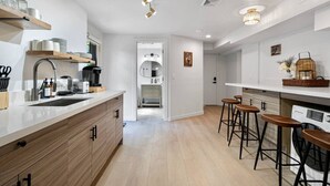 A modern kitchen with a central island, bar stools, and a dining area.
