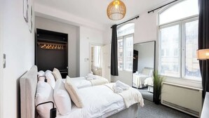 Habitación de hotel con dos camas, un ventanal grande, un espejo y una lámpara colgante.