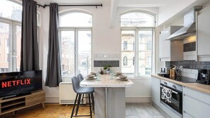 Una cocina moderna con comedor, ventanas amplias y un televisor mostrando 'NETFLIX'.
