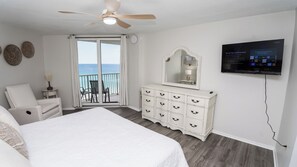 A hotel room with a bed, a dresser, a television, and a balcony with a view of the ocean. - E1102 Directly on the Beach! Dunes of Panama Vacation Rentals (Panama City)