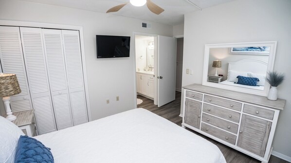 A bedroom with a bed, a dresser, a TV, and a closet.