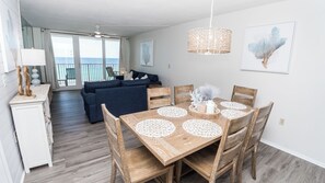 A dining area with a wooden table, white doilies, and a hanging woven light fixture. - E1102 Directly on the Beach! Dunes of Panama Vacation Rentals (Panama City)