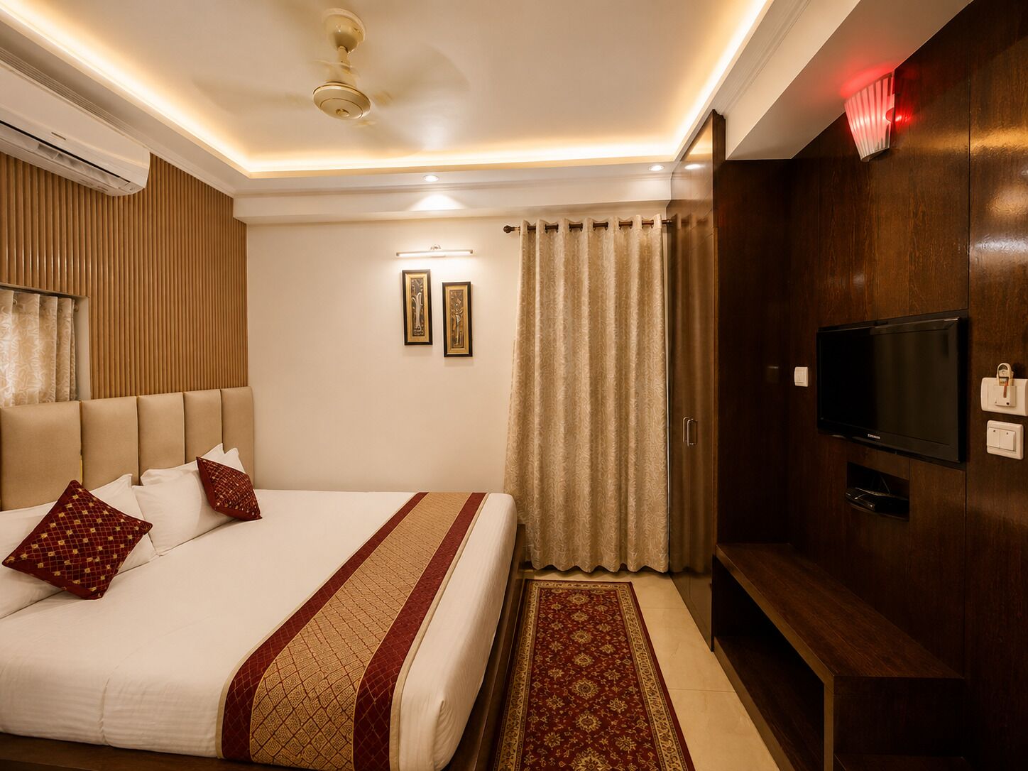 A hotel room with a bed, a television, a ceiling fan, and a window with curtains.