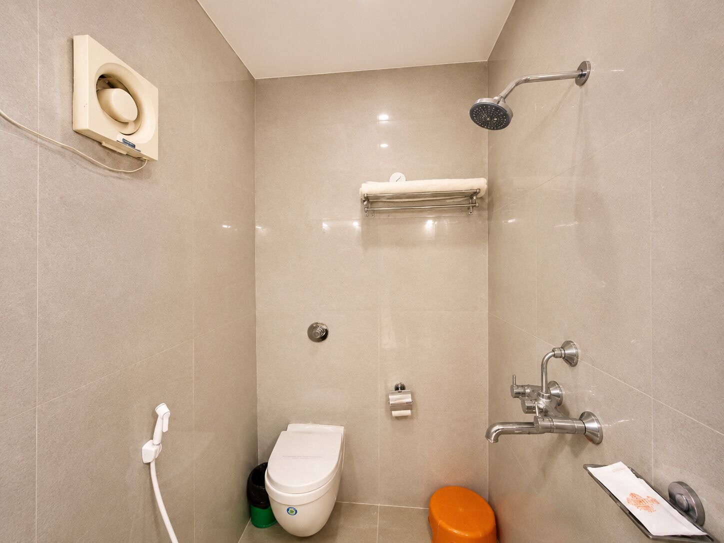 A modern bathroom with a toilet, bidet, shower, and towel rack.