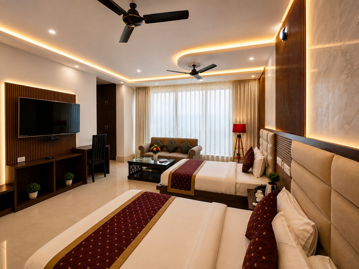 A hotel room with a large bed, a sofa, a TV, and a ceiling fan.