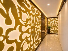 Un pasillo con un muro decorativo que presenta diseños intrincados y una planta en maceta.