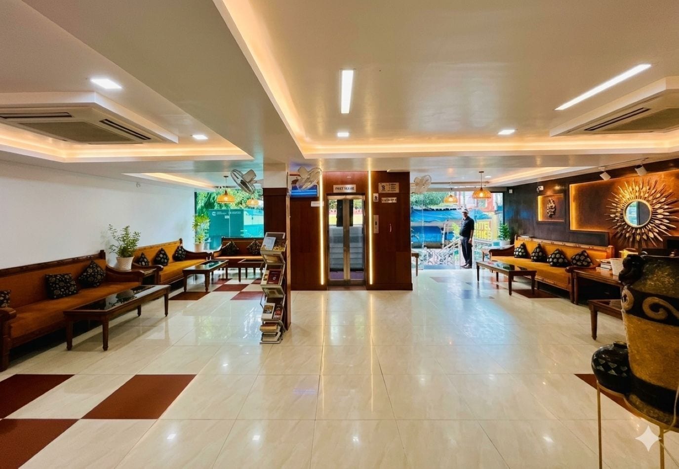A hotel lobby with a reception desk, seating area, and a staircase leading to the upper floors.
